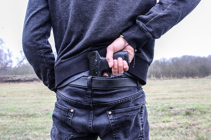 man pulling out a gun from behind